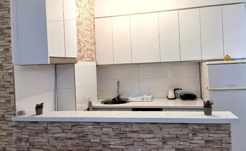 uma cozinha com armários brancos e um lavatório em Sunrise Apartment Struga em Struga