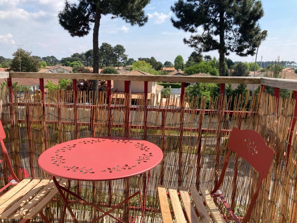 une table et des chaises rouges sur une terrasse en bois dans l'établissement T2 dans quartier résidentiel sur le Bassin Arcachon avec location de vélos, à Gujan-Mestras