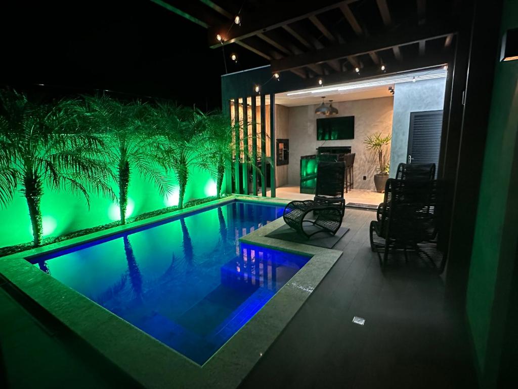 una piscina con luces verdes en una casa en Casa Aconchegante Com Piscina e Área Gourmet, en Campo Grande