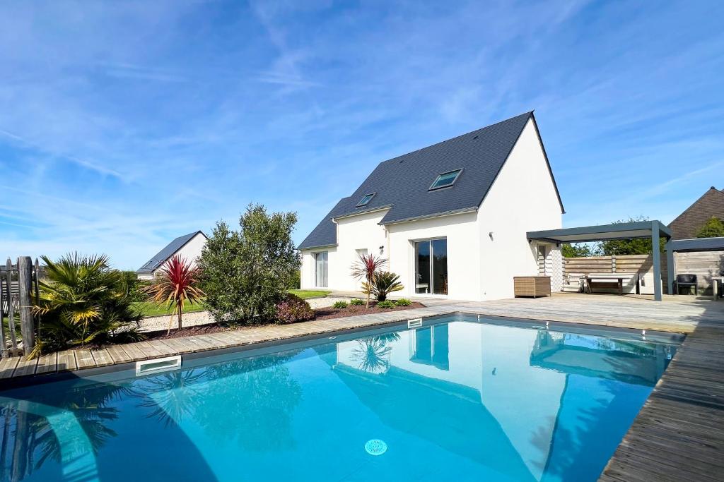 a house with a swimming pool in front of a house at Villa avec piscine privée, sauna, jardin et parking in Barneville-Carteret