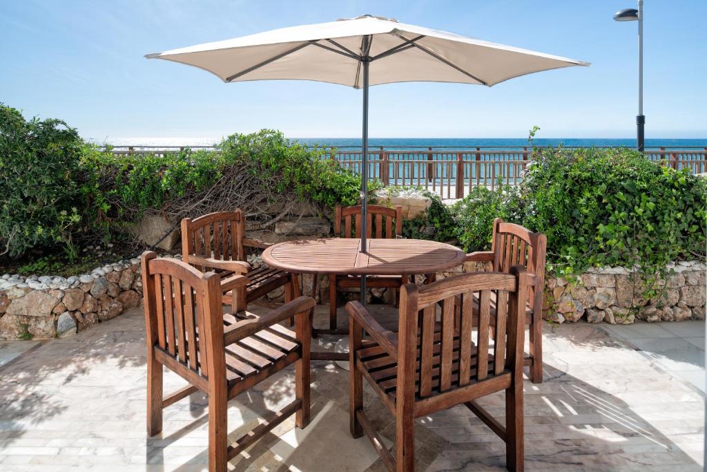 drewniany stół z 3 krzesłami i parasolem w obiekcie Casa Honey w Marbelli