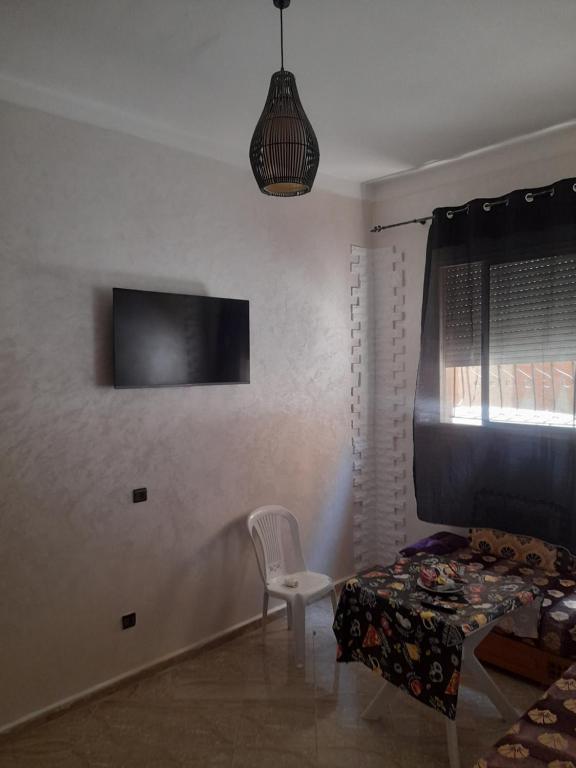 a bedroom with a chair and a tv on the wall at Apartment Surf in Skhirat