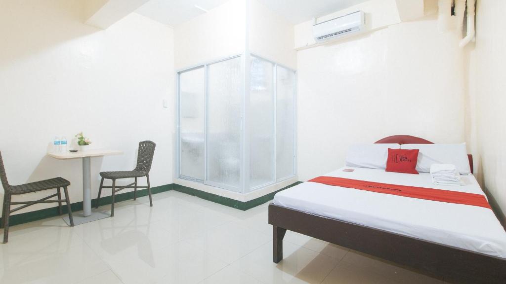 1 dormitorio con 1 cama, mesa y sillas en RedDoorz @ Western Bicutan Transients Inn, en Manila