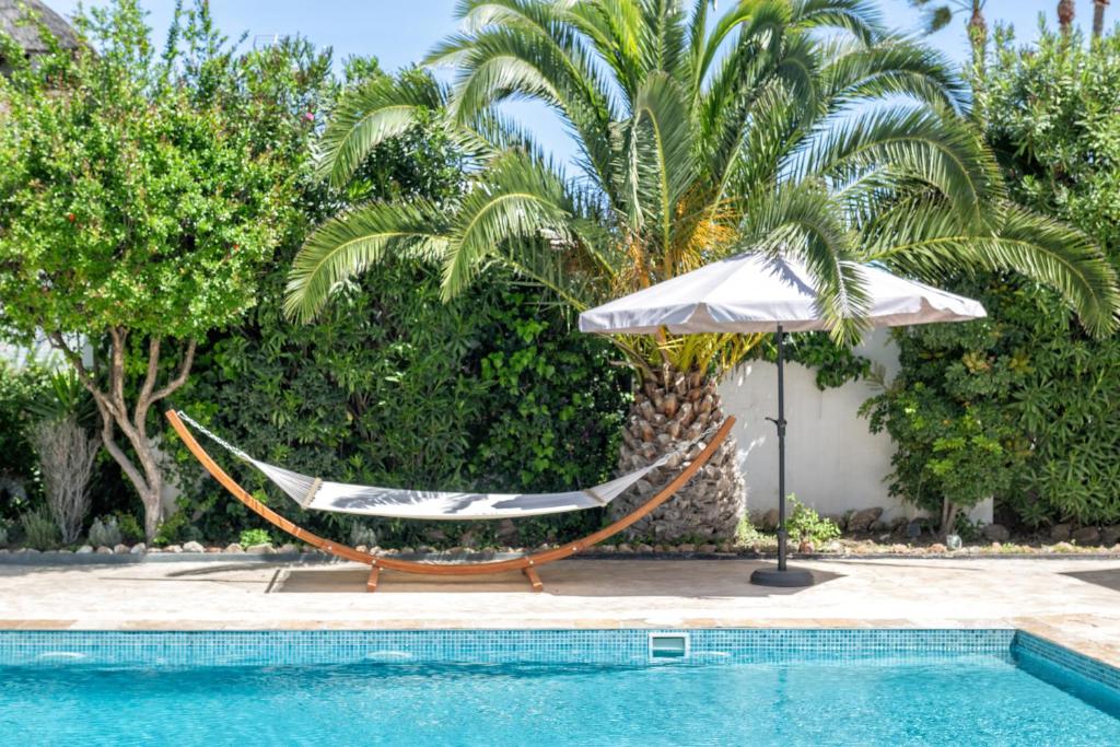 a hammock and an umbrella next to a pool at Casa Honey in Marbella