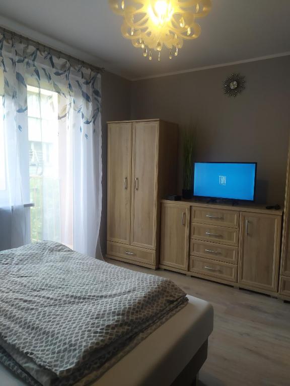 a bedroom with a bed and a flat screen tv at Studio Niebieskie in Wałbrzych