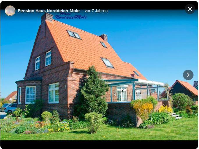 een groot bakstenen huis met een oranje dak bij Pension Haus Norddeich Mole in Norddeich