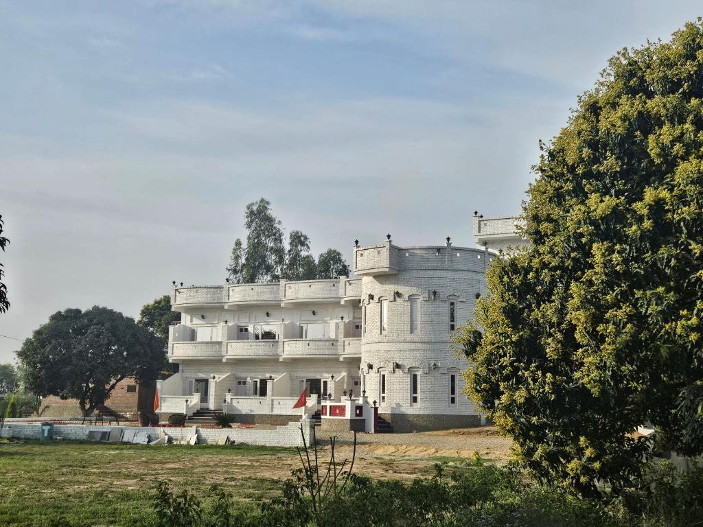 un gran edificio blanco en medio de un campo en Jairaj Ecostay, en Shāmli