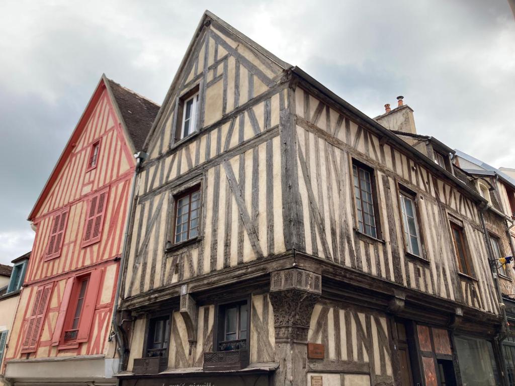 un vieux bâtiment en bois avec un bâtiment rouge dans l'établissement AU LION D OR, à Auxerre