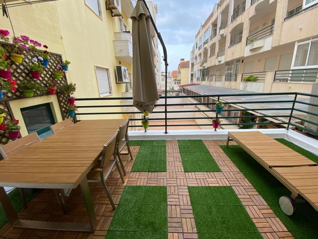 patio z ławkami i parasolem na balkonie w obiekcie Atlantic Lodge, 1ª linha de praia! w Costa de Caparica