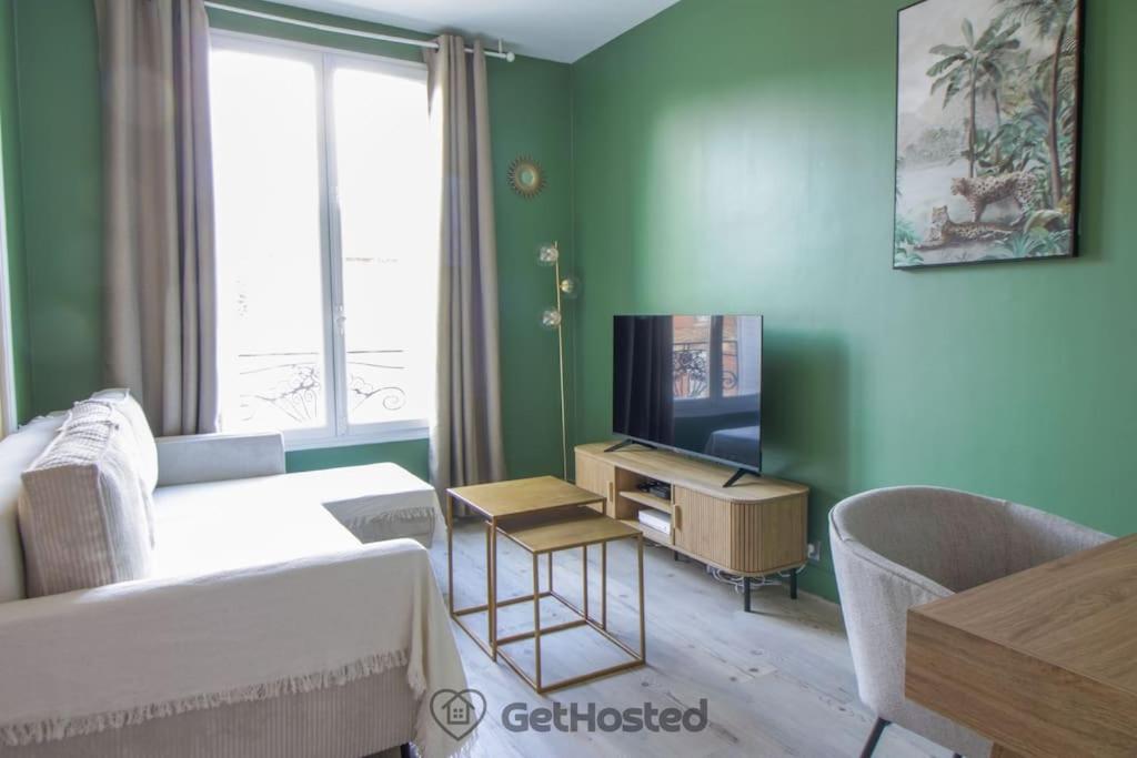 ein Wohnzimmer mit einem Sofa und einem TV in der Unterkunft Charming Flat at the gates of Paris - GetHosted in Asnières-sur-Seine