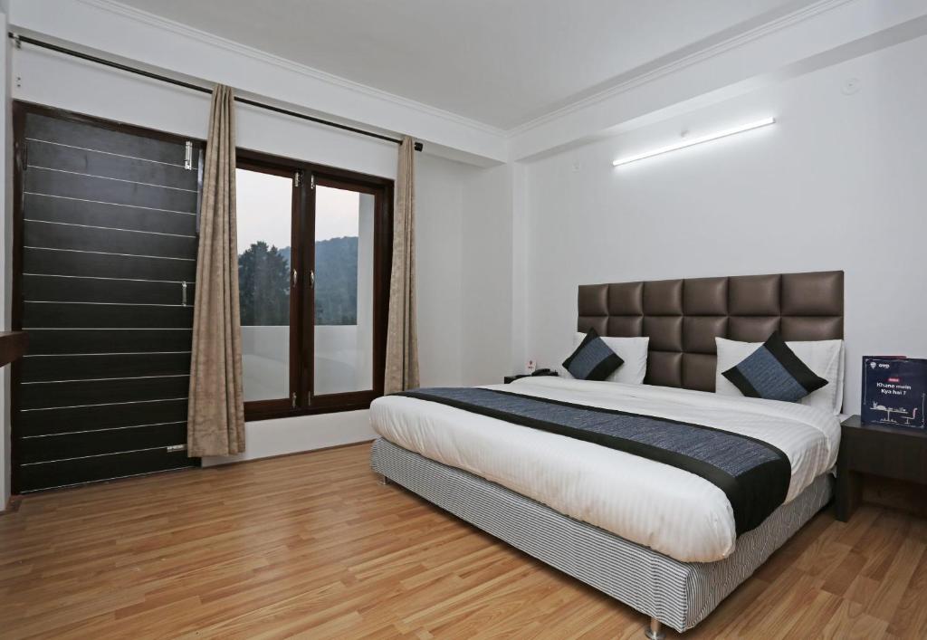 sypialnia z dużym łóżkiem i dużym oknem w obiekcie Summer King w mieście Nainital