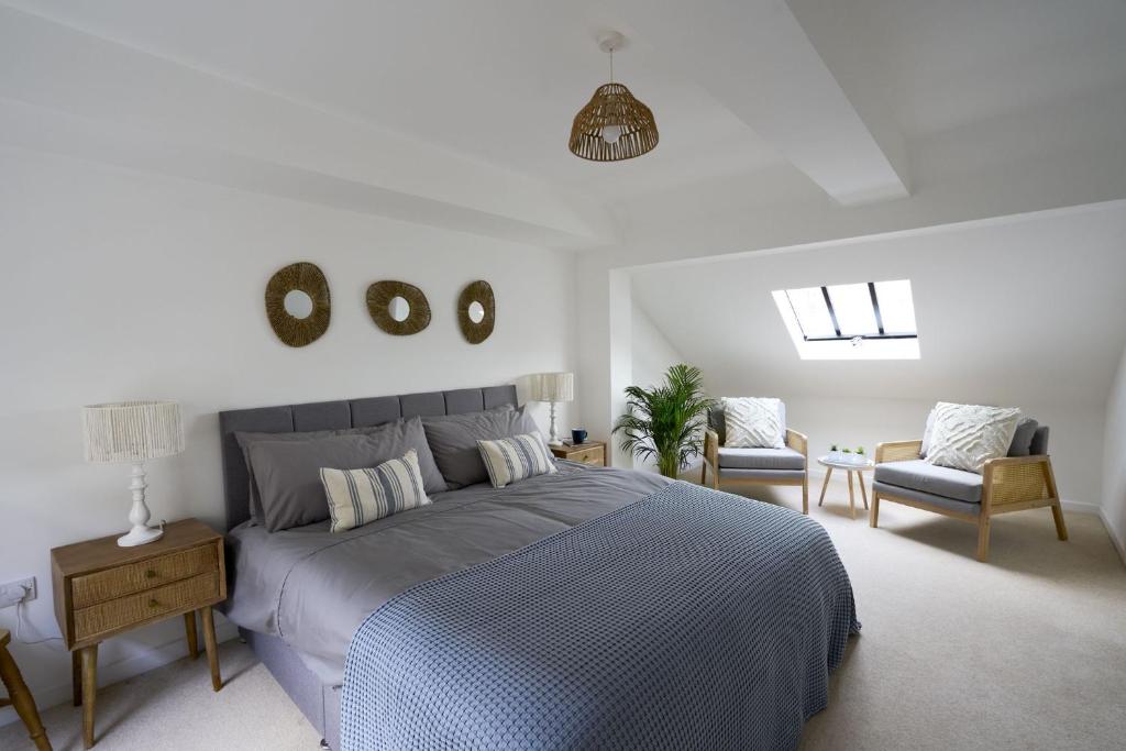 a bedroom with a bed and a couch and chairs at Surf Cottage in Cromer
