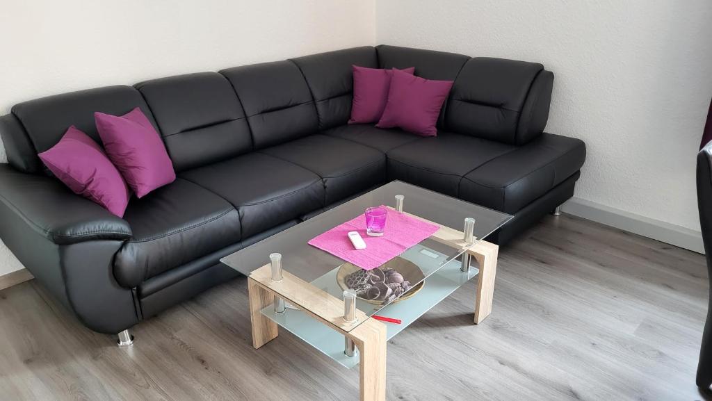 Sofá negro con almohadas moradas y mesa en Fewo Kaiser Wohnung Stella, en Dresden
