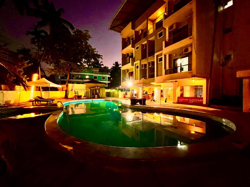 a swimming pool in front of a building at night at Hamilton Hotel & Resort Goa in Goa