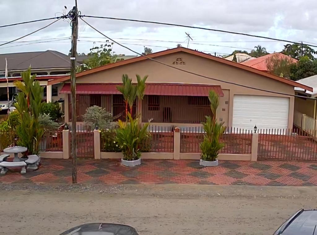 a house with a fence and plants in front of it at Vakantiehuis Paramaribo in Paramaribo