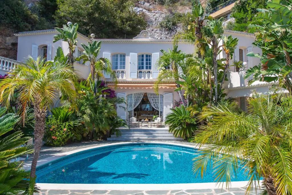an exterior view of a house with a swimming pool and palm trees at Villa de luxe à Cap-d'Ail in Saint-Antoine