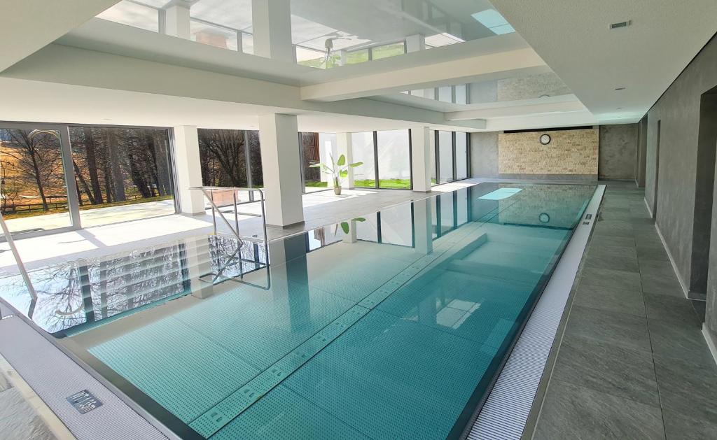 an indoor swimming pool with blue water in a building at Kurhotel Schluchsee App 1321 - Schwarzwälder Kirsch - mit Indoorpool, Schluchsee in Schluchsee