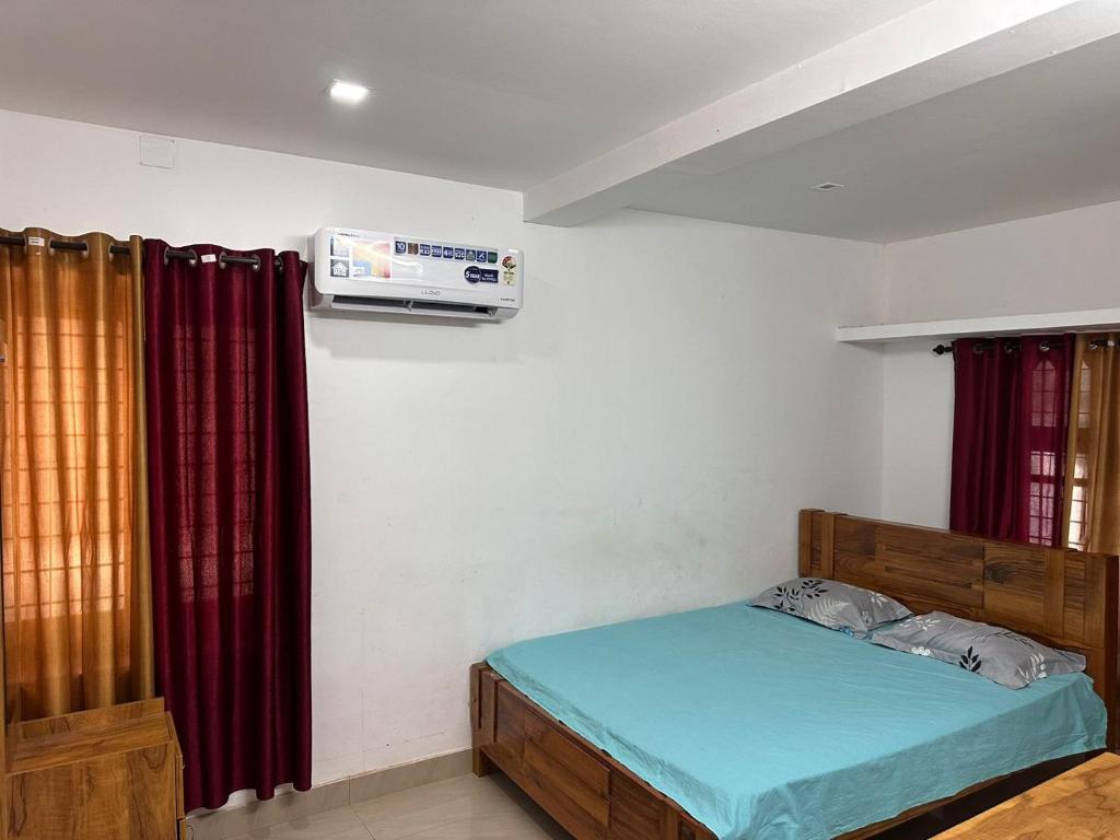 a bedroom with a bed and a air conditioner on the wall at Whitehouse Homestay-Iqra Hospital Calicut in Kozhikode