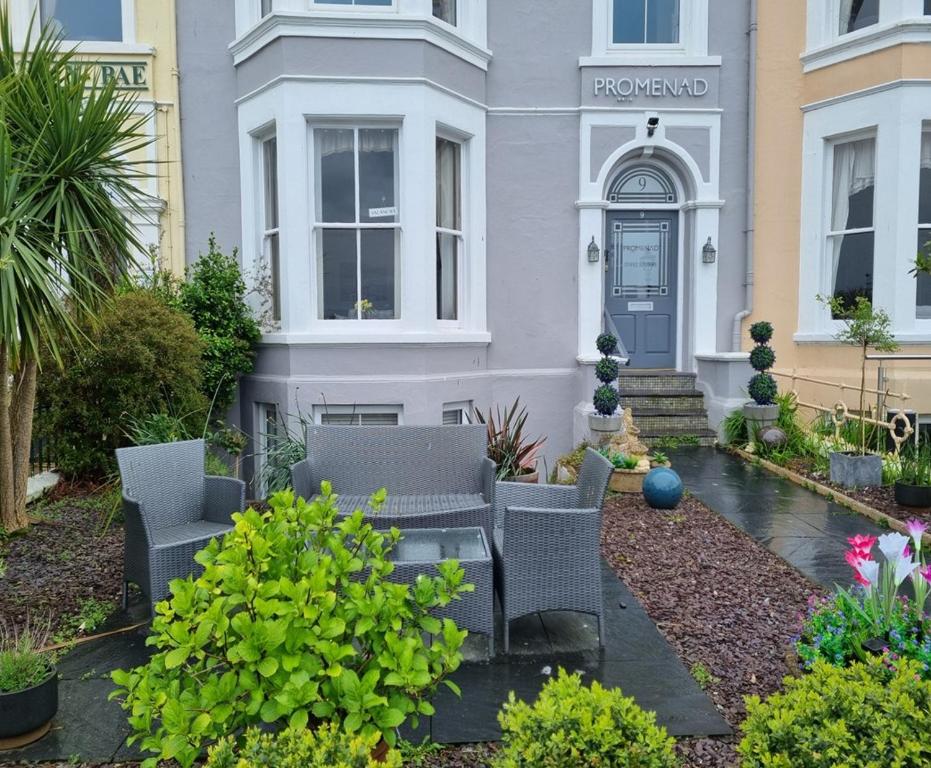 a house with chairs and a table in front of it at Promenâd Bed & Breakfast in Llandudno