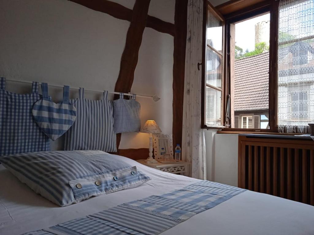 um quarto com uma cama e uma grande janela em Appartements & Chambres Les Loges du Capucin em Kaysersberg