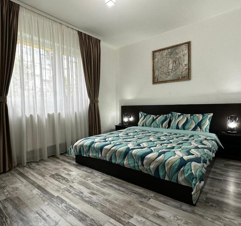 a bedroom with a bed and a large window at Comfort Apartment in Târgovişte