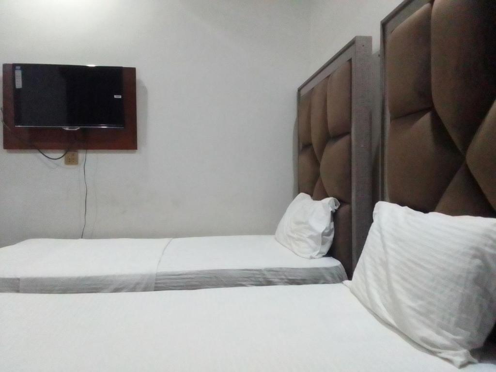 um quarto de hotel com duas camas e uma televisão de ecrã plano em Dove Inn Family Residency Johar Town em Lahore