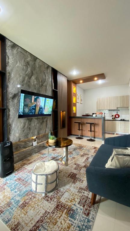 a living room with a couch and a tv on a wall at Mallory Villa in Batu