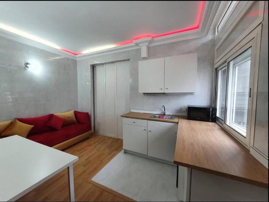 Studio Cosy moderne et climatisé في الرباط: مطبخ مع أريكة حمراء في غرفة المعيشة