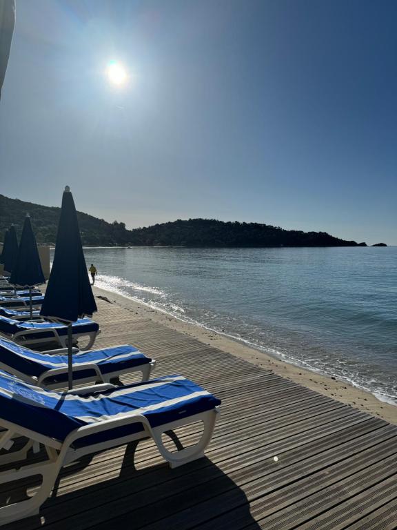 a row of lounge chairs and umbrellas on a beach at Grand Hotel Moriaz in Le Lavandou