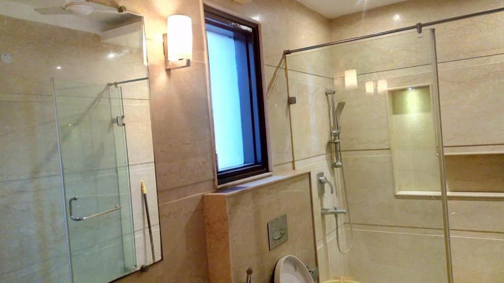 a bathroom with a shower and a toilet and a window at Luxury Flat in Faridabad