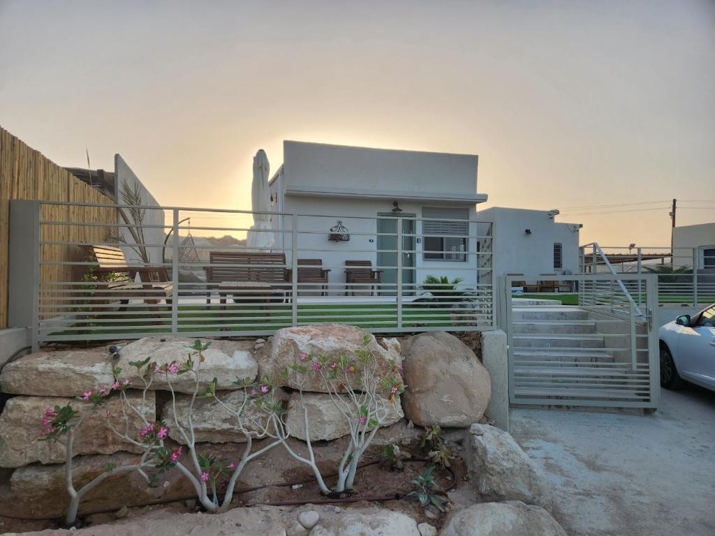 a house with a fence and some rocks and a car at בצל ההר in Ein Tamar 