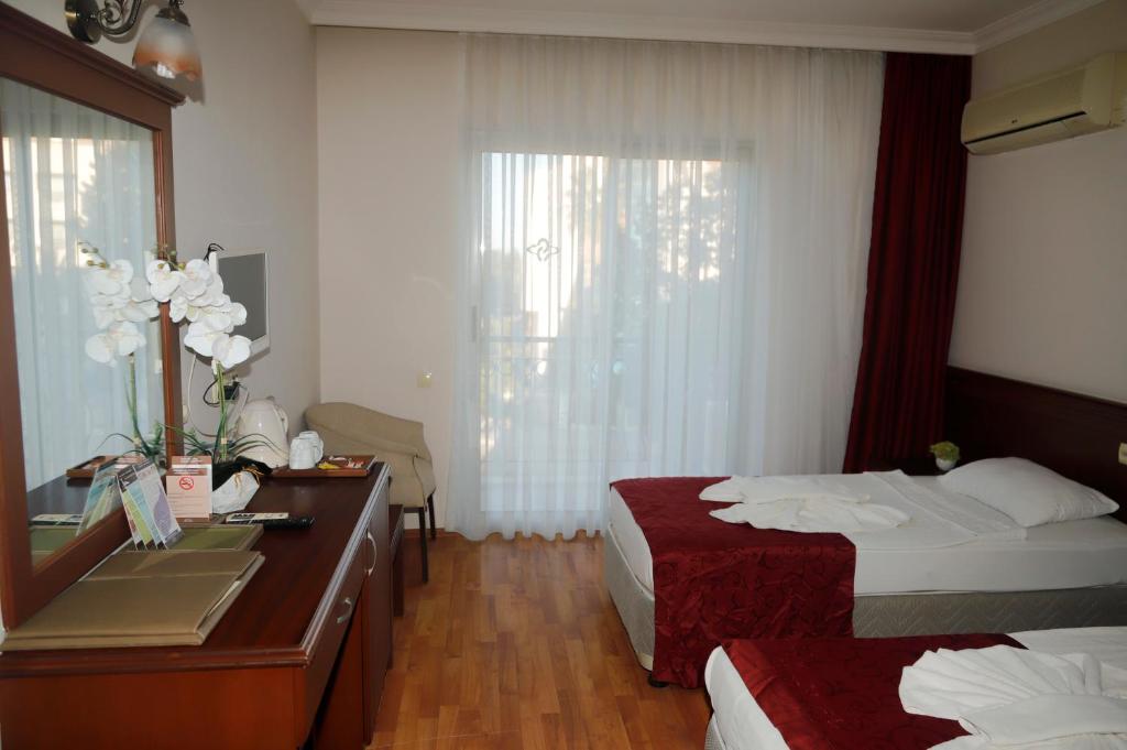 a hotel room with two beds and a desk at Sea point Quality Resort in Antalya