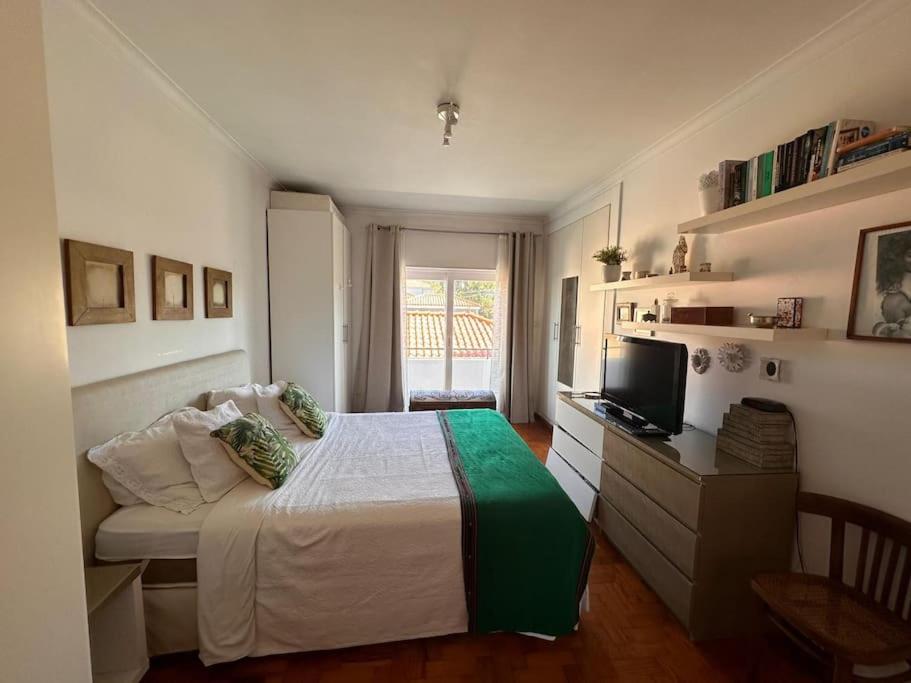 een slaapkamer met een bed en een bureau met een televisie bij Nice Villa in Cascais, near the center and beaches, but in a very quite neighborhood in Cascais