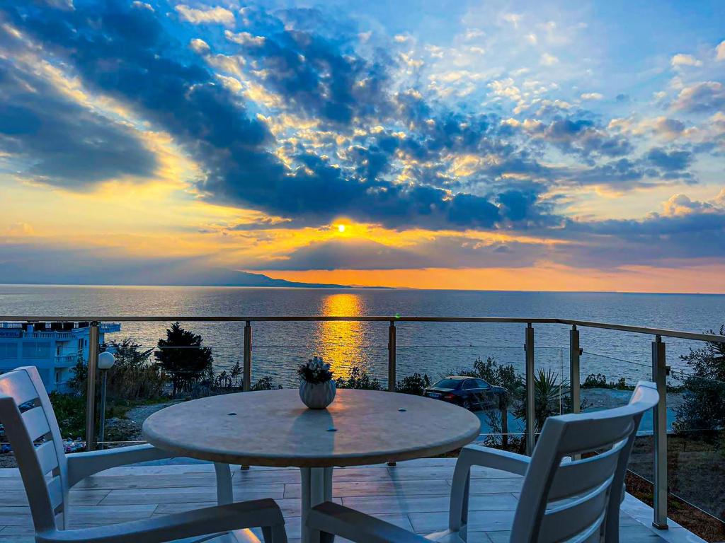 einen Tisch und Stühle auf einem Balkon mit Blick auf den Sonnenuntergang in der Unterkunft Sunny Coast Apartments in Sarandë