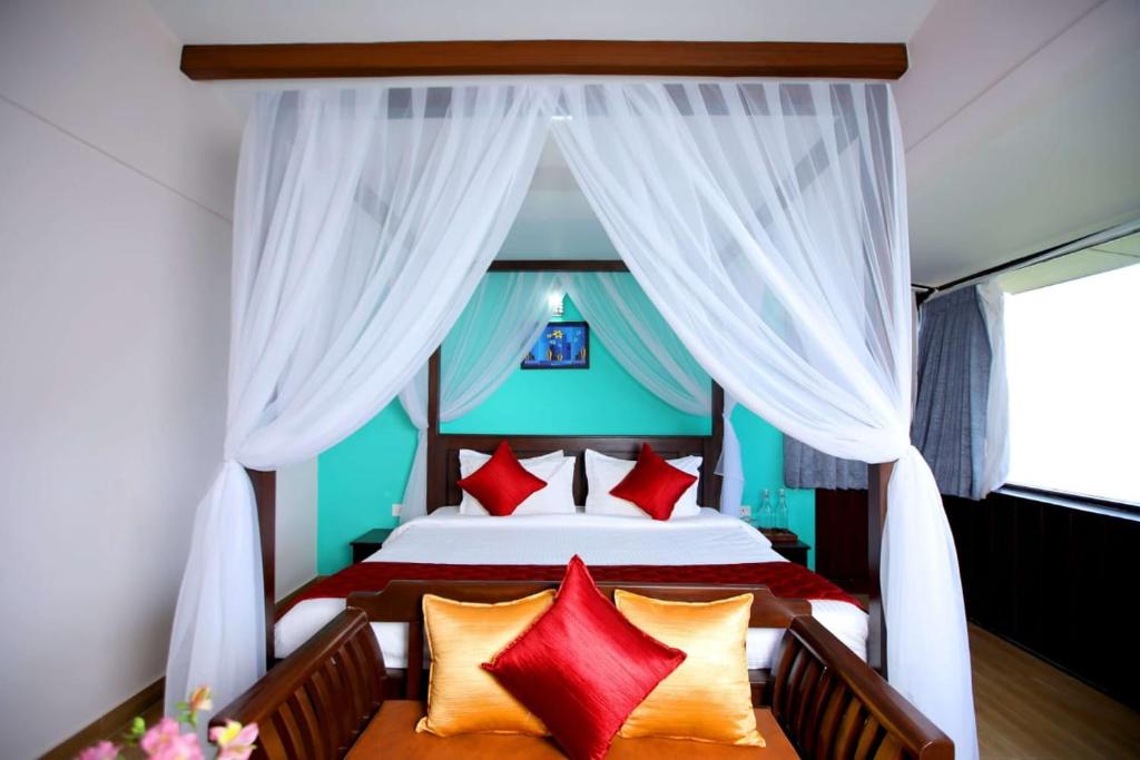 um quarto com uma cama grande e almofadas vermelhas em The Garudan Mountain View Residency em Kodaikanal