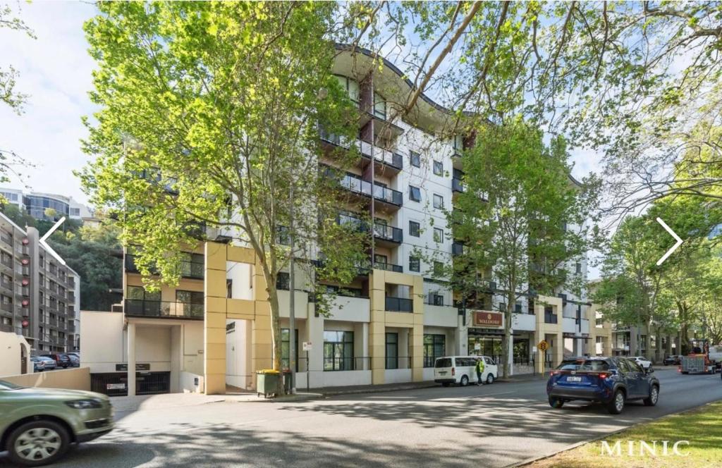 an apartment building with cars parked on a street at Waldorf Hotel Apartments In Perth City Centre in Perth