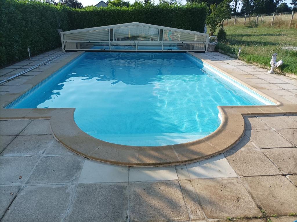 uma piscina com uma casa de vidro em cima em Maison de campagne avec piscine em Le Blanc