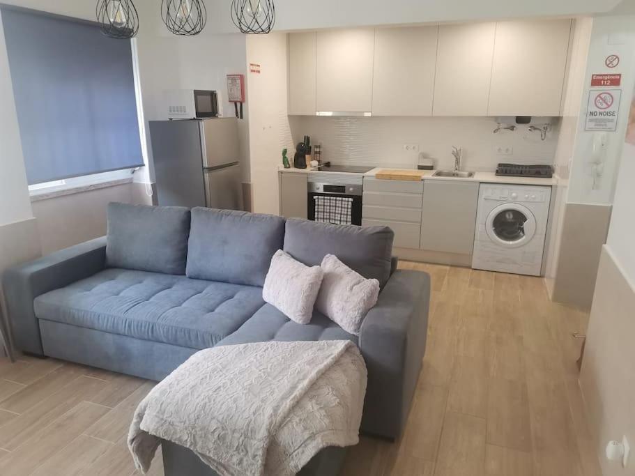 a living room with a blue couch and a kitchen at Enjoy Lisboa 2! - Near Metro in Amadora