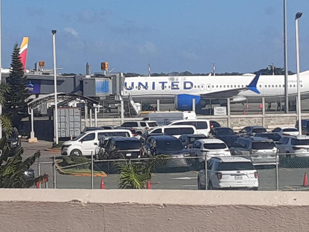 a united airplane parked in a parking lot with cars at transporte Joaquín me dedico al servicio de taxi desde el Aeropuerto las Américas a todas partes del país in Santo Domingo