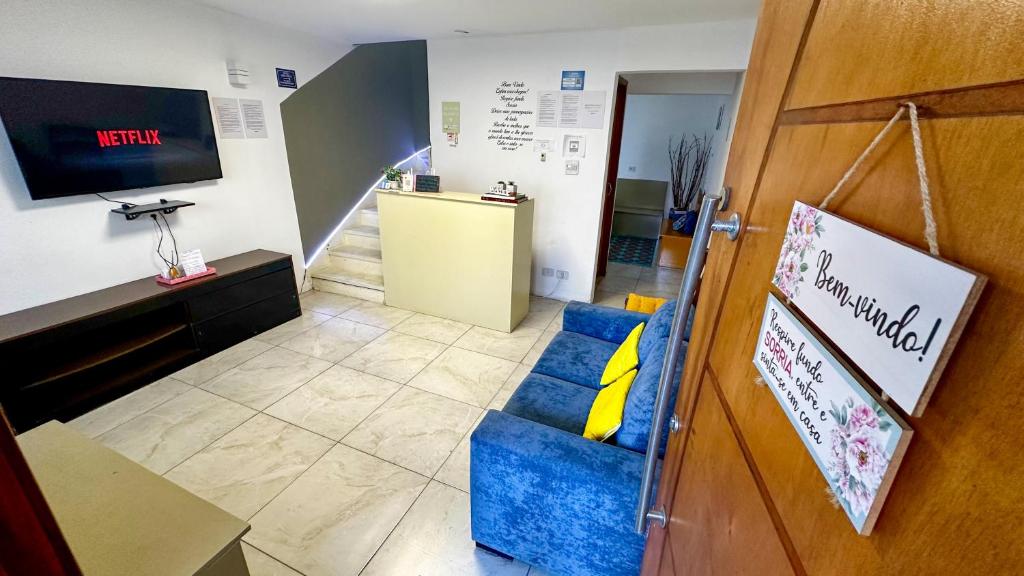 a waiting room with a blue couch and a television at Hostel Welcome SP - Congonhas in Sao Paulo