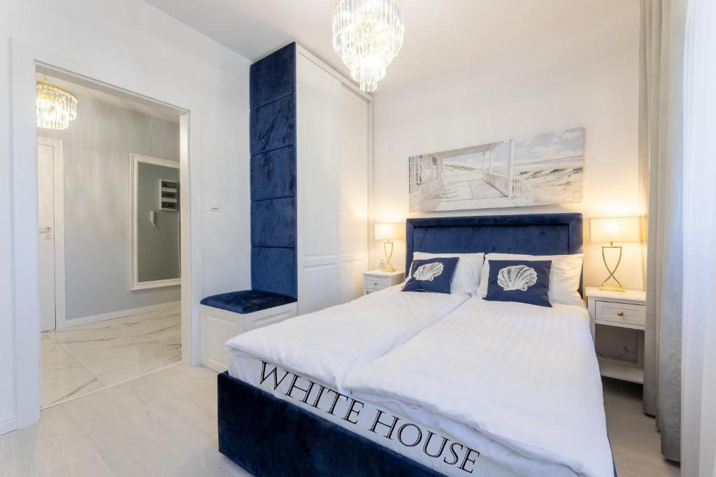 Cette maison blanche comprend une chambre dotée d'un lit bleu et blanc. dans l'établissement Apartament White House Ustka Granatowy 2B, à Ustka