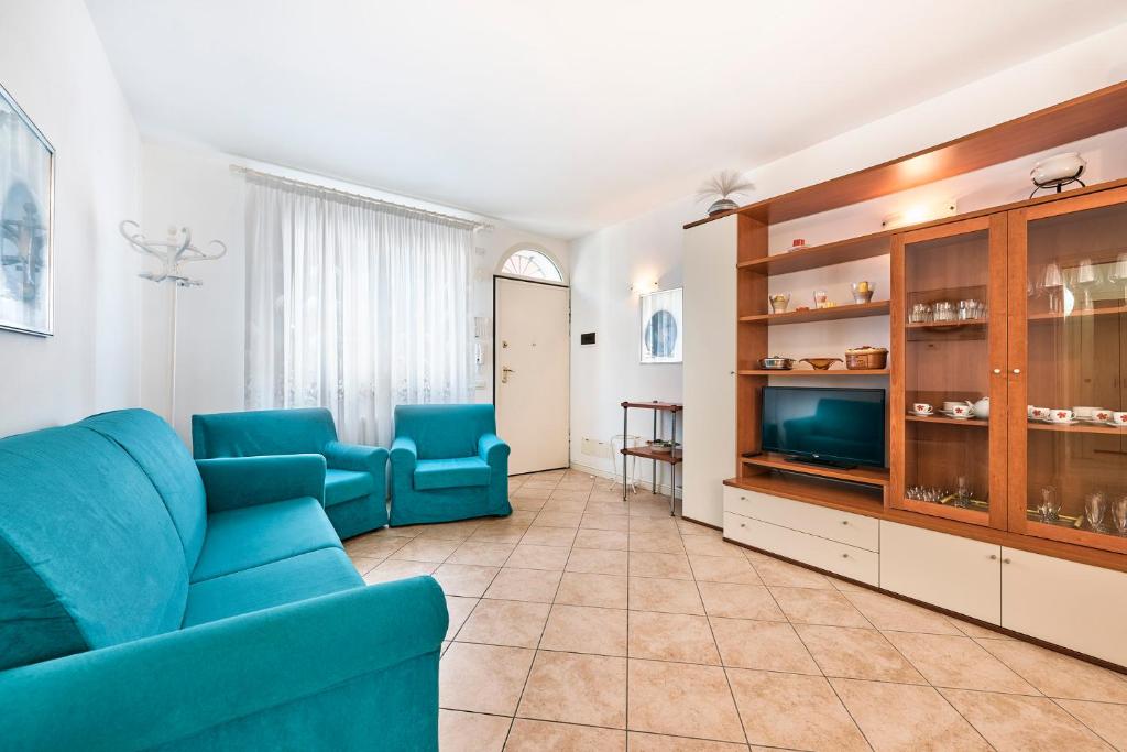 a living room with a blue couch and a tv at Jesolo Pines Beach House - Host Solution in Lido di Jesolo