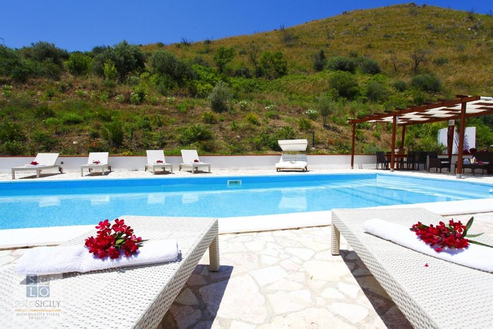 een zwembad met witte stoelen en een berg bij villa costanza in Cefalù