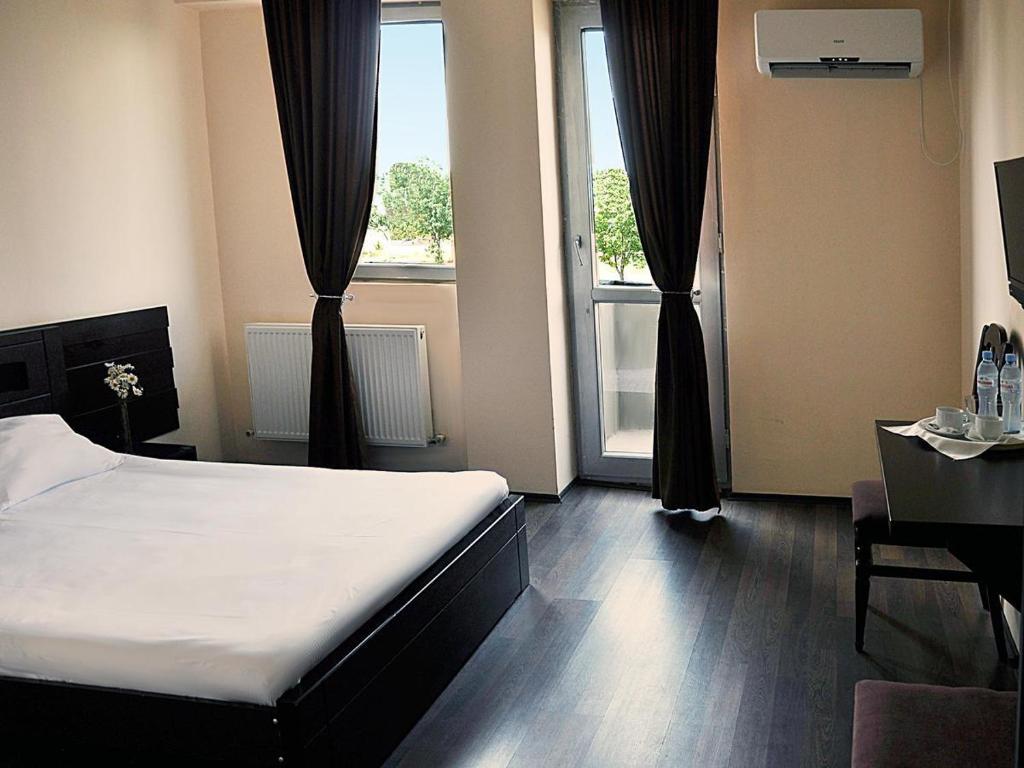 1 dormitorio con cama, mesa y ventana en Hotel Grand, en Nizhnyaya Alekseyevka