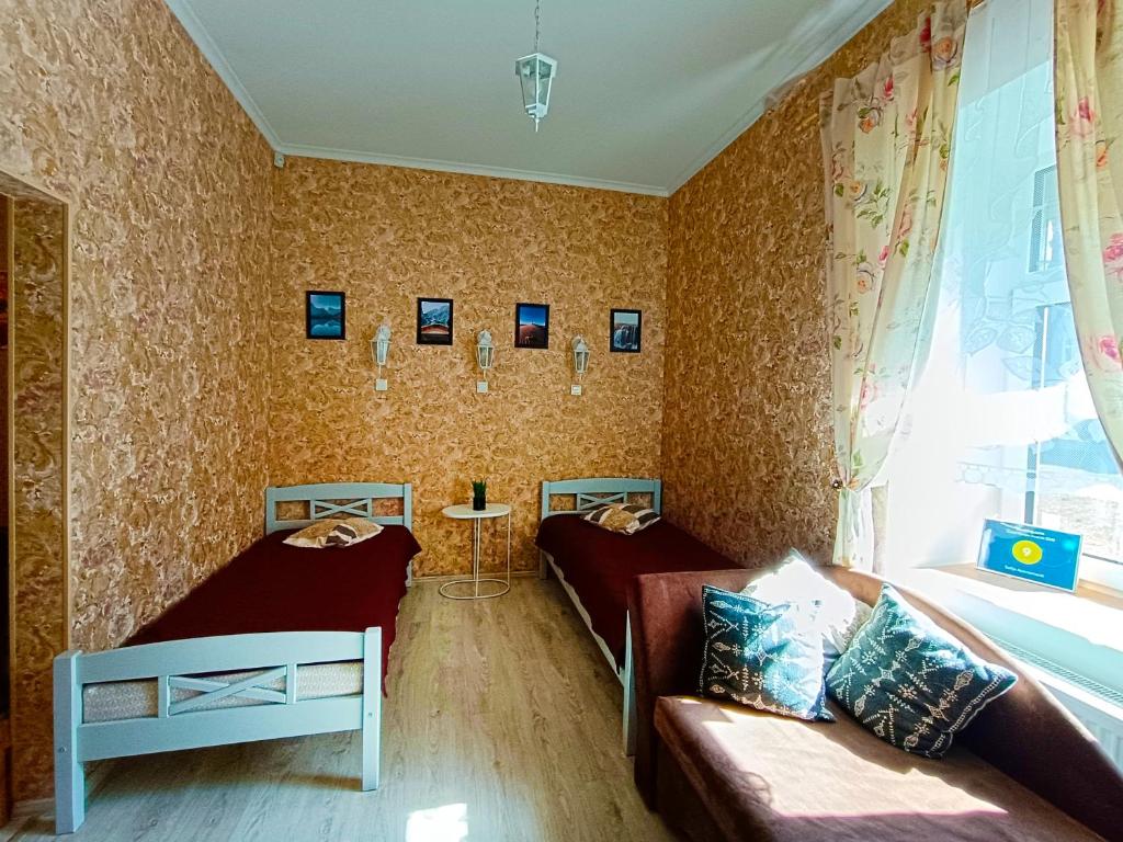 una camera con due letti, un divano e una finestra di Sofija apartamenti a Daugavpils