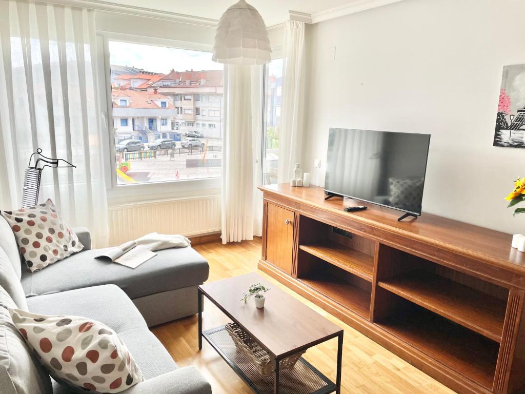 a living room with a couch and a television at Apartamento San Juan. Piscina y Parking privado. in San Juan de la Arena
