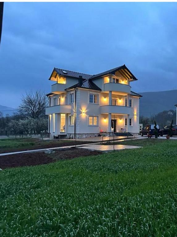 a large white house with lights on in a field at Villa Morina in Tropojë