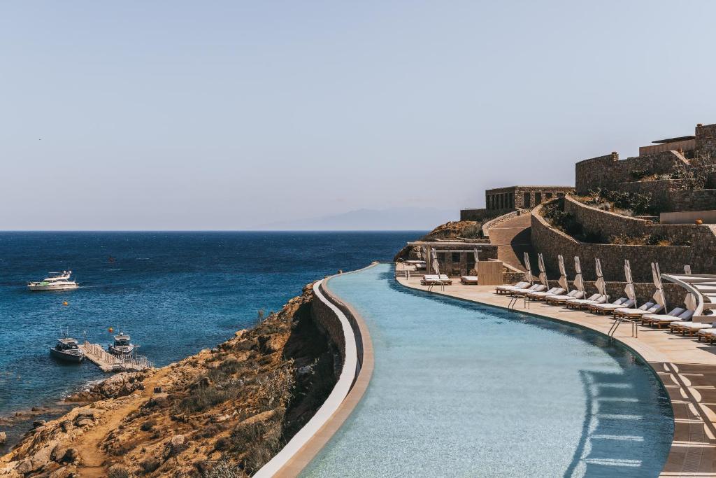 a pool on the side of a cliff next to the ocean at Cali Mykonos in Kalafatis