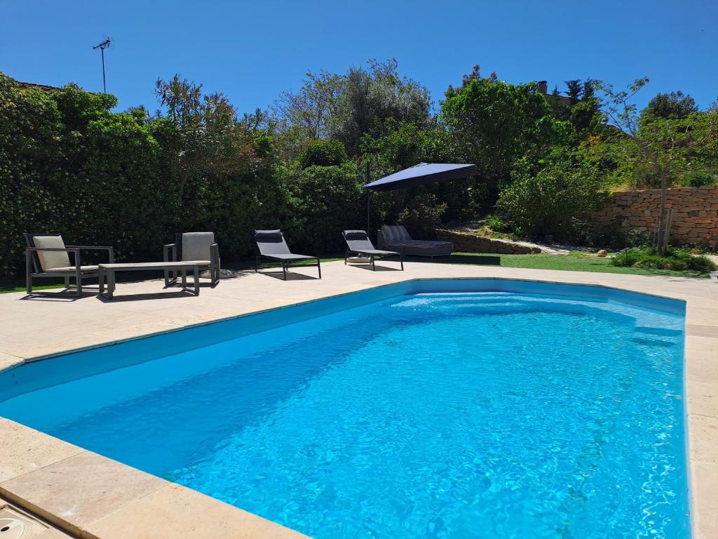 una piscina blu con sedie e tavolo di Chambre indépendante climatisée, terrasse 100M2 et salle d'eau a Saint-Cyr-sur-Mer