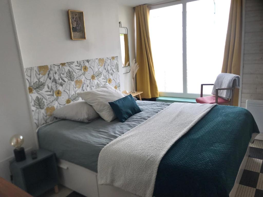 a bedroom with a bed with a blue blanket and a window at La Loge de Marguerite in Champtoceaux